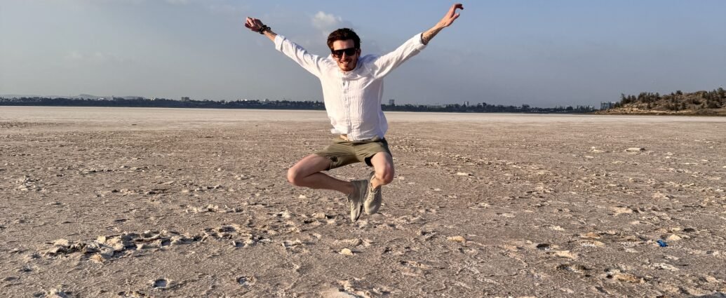 Person jumping at Larnaca Salt Lake surrounded by salt formations and open landscape in Cyprus