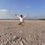 Person jumping at Larnaca Salt Lake surrounded by salt formations and open landscape in Cyprus