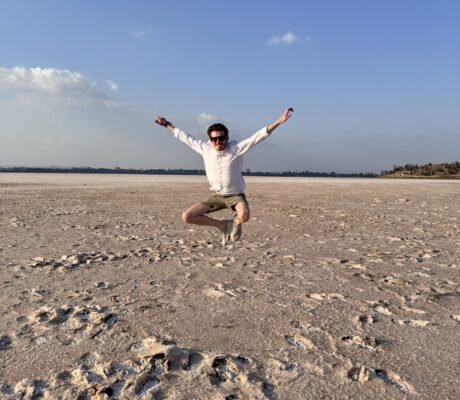 Person jumping at Larnaca Salt Lake surrounded by salt formations and open landscape in Cyprus